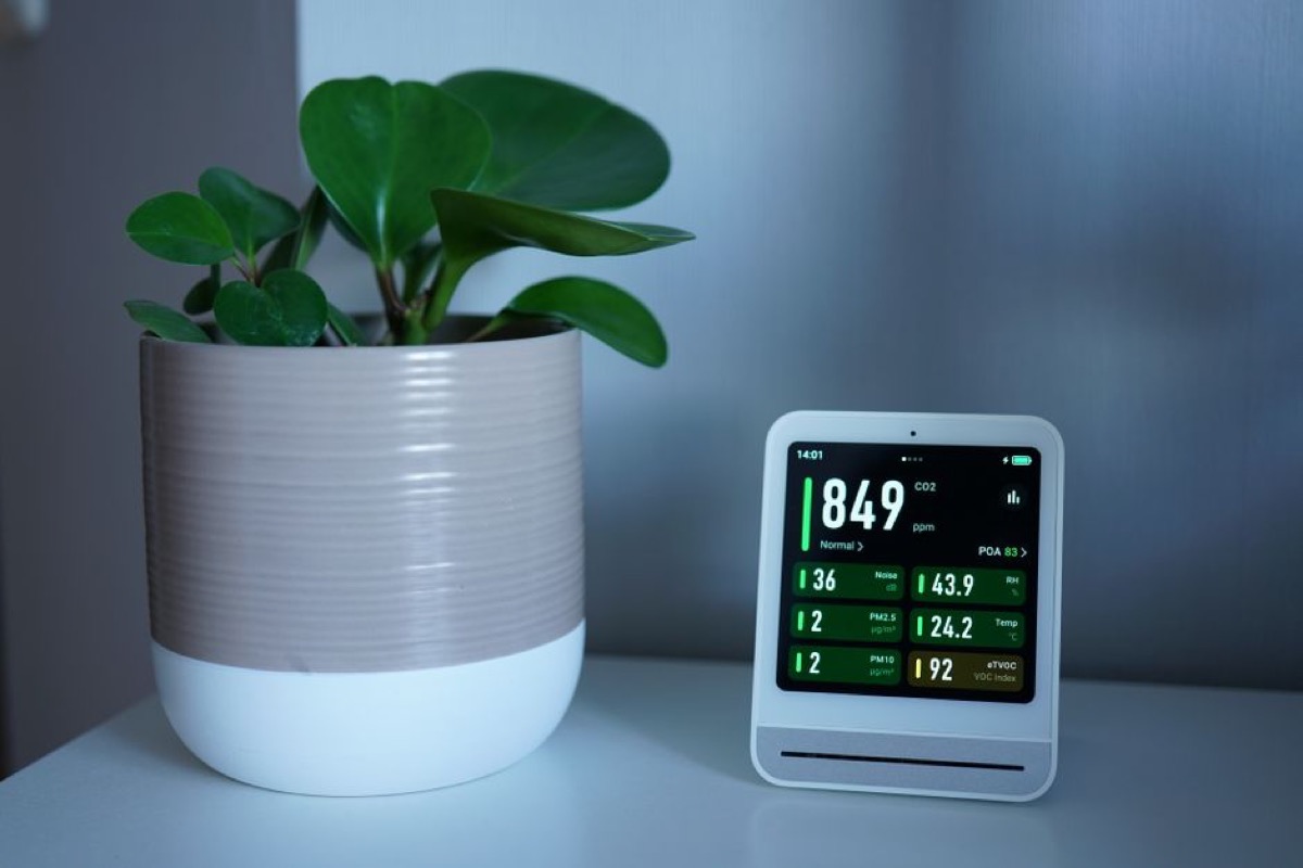 Air quality monitor on a home office desk showing real-time indoor PM2.5 readings